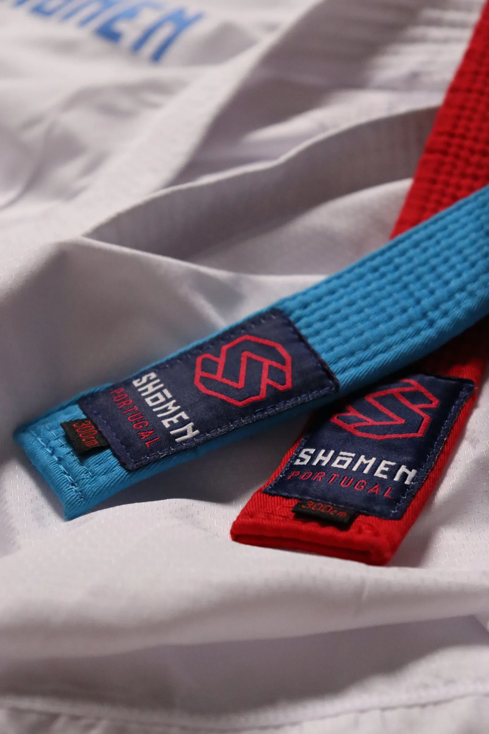 Cintos de kumite azul e vermelho Shomen sobre um kimono branco