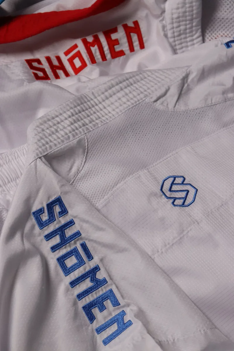 Pormenor das letras Shomen bordadas a azul na manga de um kimono branco